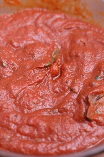 A bowl of tomato sauce on a table.