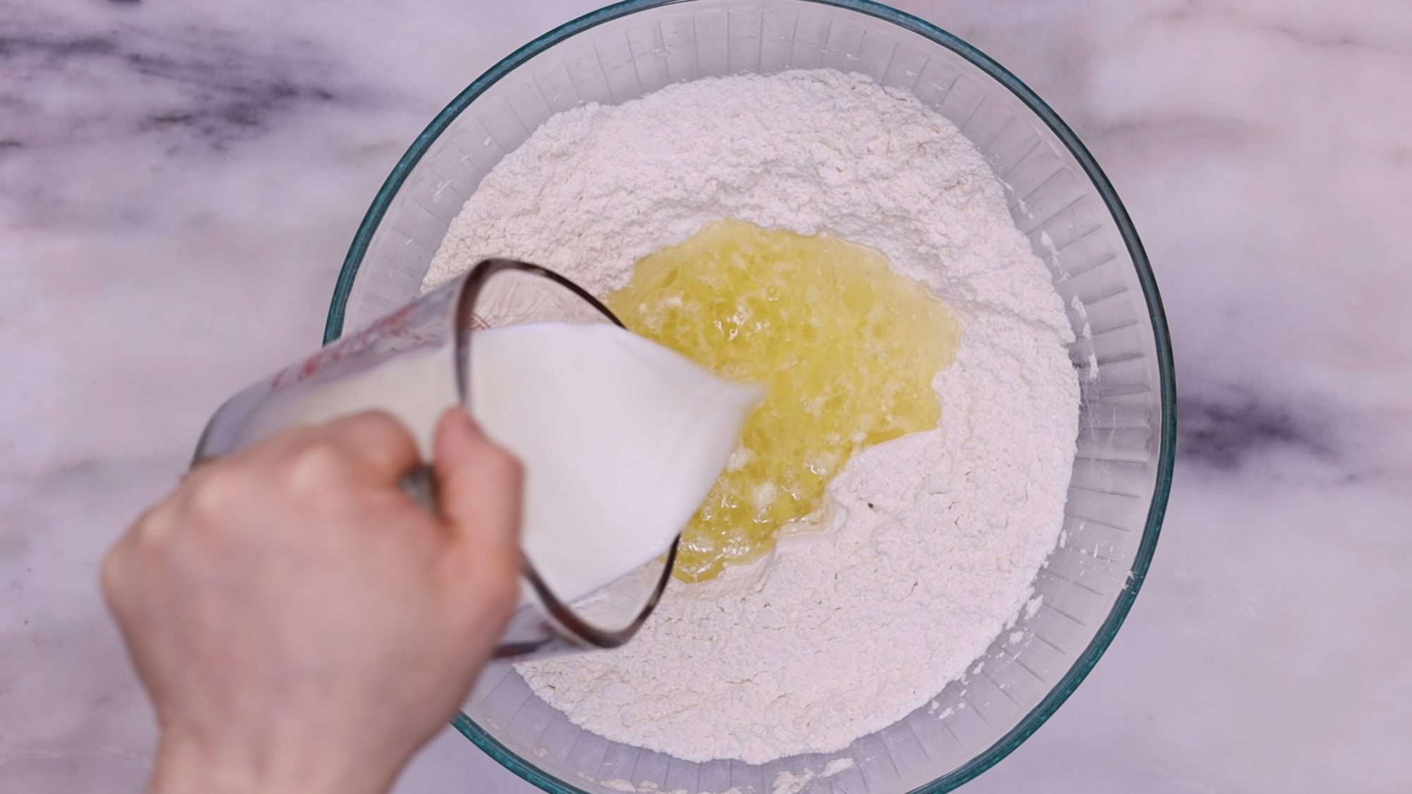 Add the milk and water while stirring continuously with a wooden spoon. Continue this process until you achieve a dough that is wet, stretchy, and sticky.