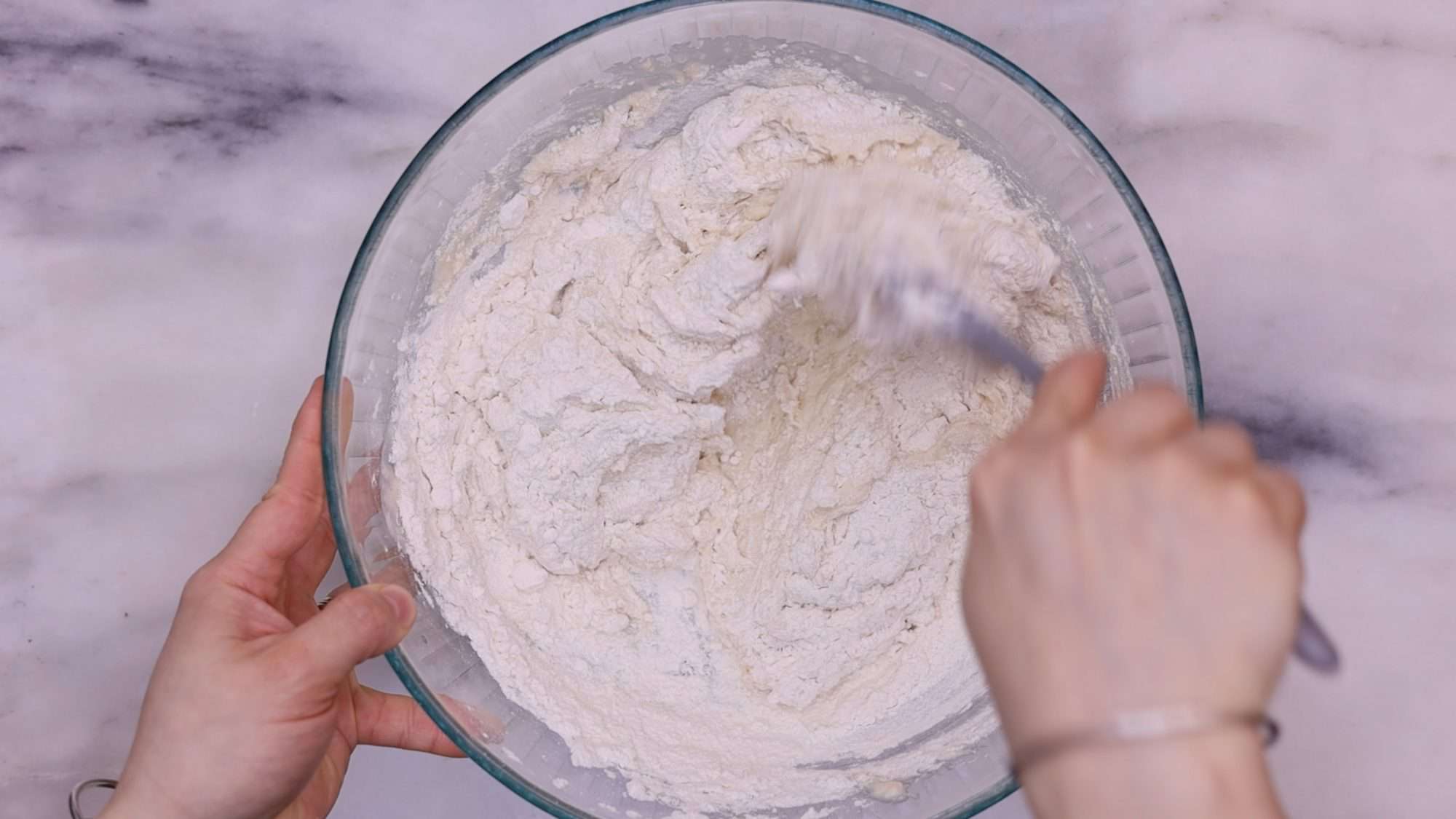 Add the milk and water while stirring continuously with a wooden spoon. Continue this process until you achieve a dough that is wet, stretchy, and sticky.