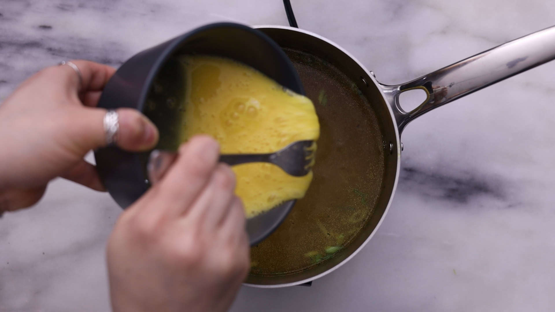 Beat eggs with salt, pour into the soup to form ribbons, and stir gently.