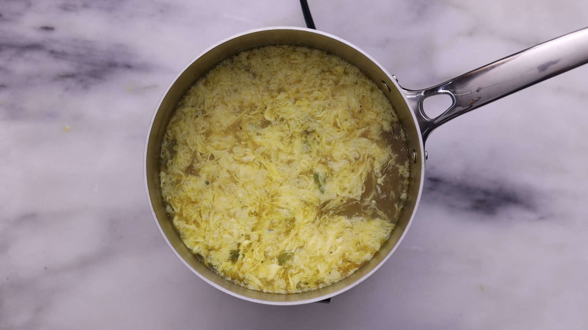 Beat eggs with salt, pour into the soup to form ribbons, and stir