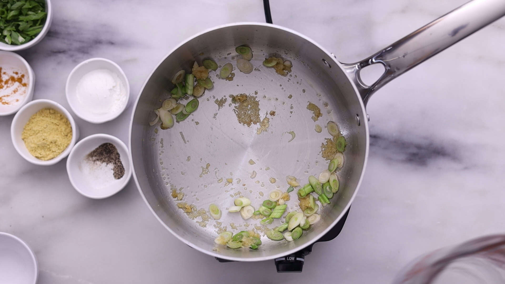 Heat oil and sauté garlic, ginger, and white parts of green onions until fragrant.