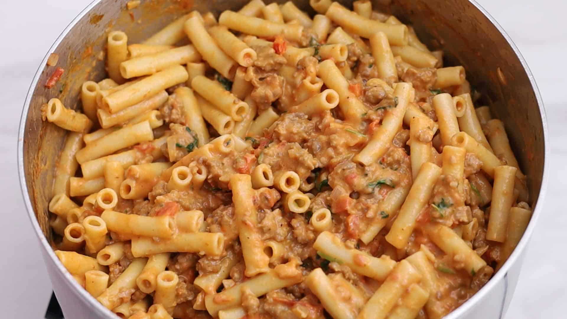 Mezclar la salsa con la pasta y transferir la mitad a la fuente de horno