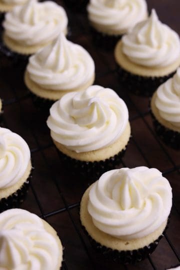 Cupcakes de Vainilla in a cooling rack with white frosting on top.