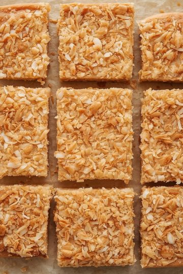 Cocada coconut squares arranged on parchment, top-down view, soft studio light, warm beige and caramel color, crumbly edges, toasted coconut flecks, minimal styling, copy space, commercial food photo