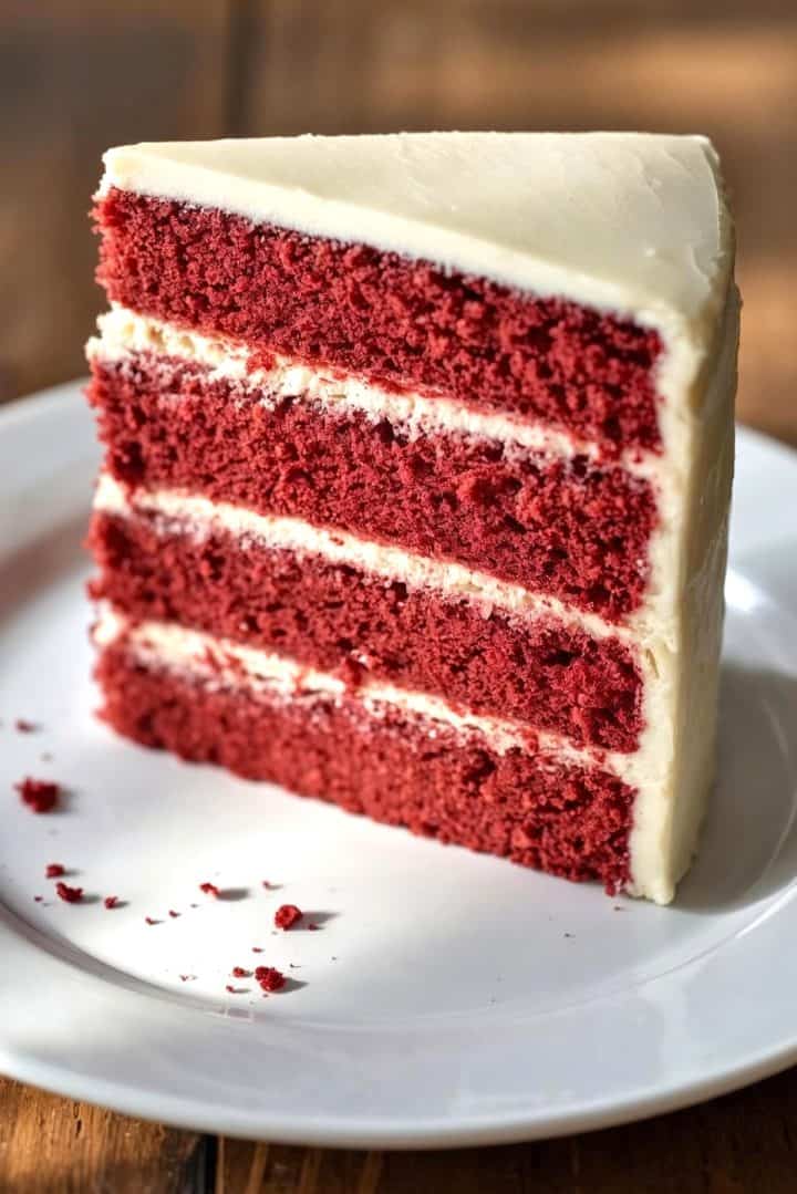 45-degree angle of a tall slice of four-layer red velvet cake with cream cheese